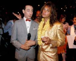 Comedian & actor Paul Reubens (1952 - 2023) (left), as his character Pee-Wee Herman, and singer David Lee Roth pose together at the premiere of the movie 'Pee-Wee's Big Adventure,' at Gruman's Chinese Theater, Los Angeles, August 1, 1985. (Photo by Richard E. Aaron/Redferns)